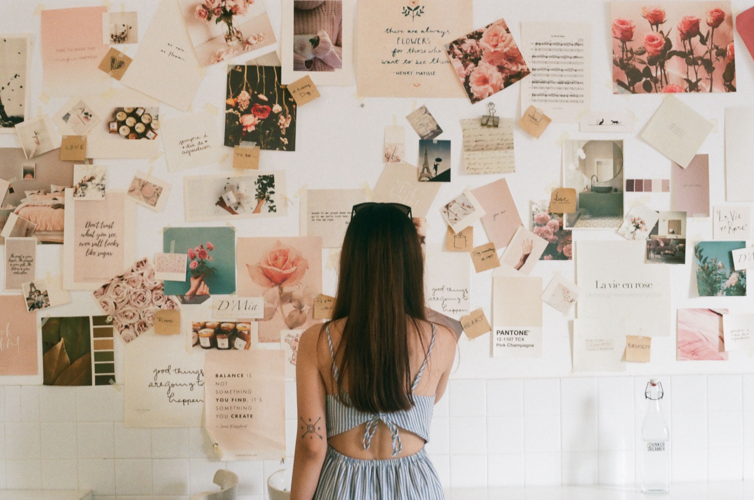 A woman standing before a wall covered in an inspiration mood board